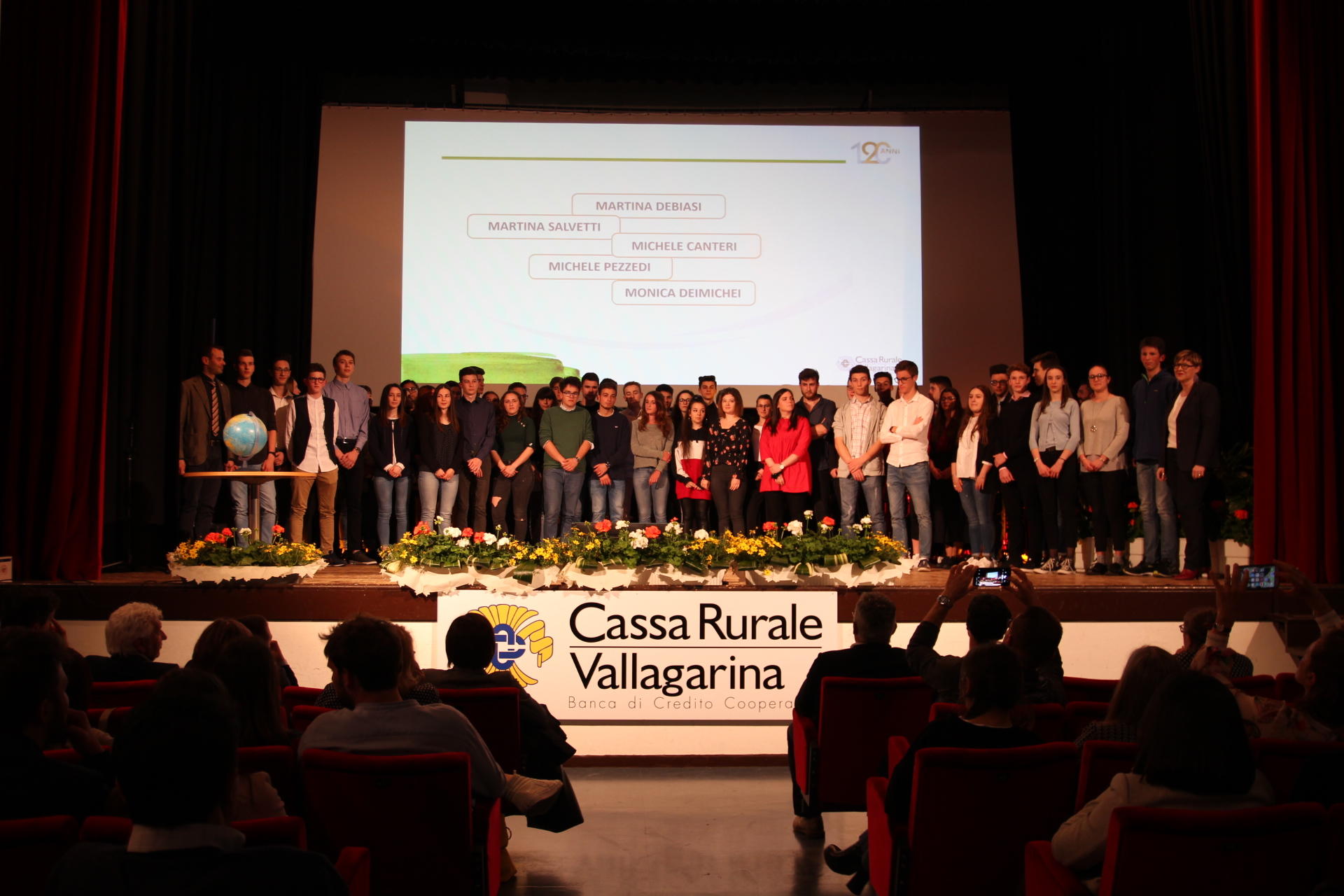 Sono 120 i giovani premiati dalla Cassa Rurale Vallagarina per il loro impegno in ambito formativo. A congratularsi con loro anche l’ex calciatore Damiano Tommasi e lo scrittore Riccardo Bertoldi. Al termine della cerimonia di consegna dei premi allo studio, la premiazione del concorso ideato dal Gruppo giovani LINKontr@giovani